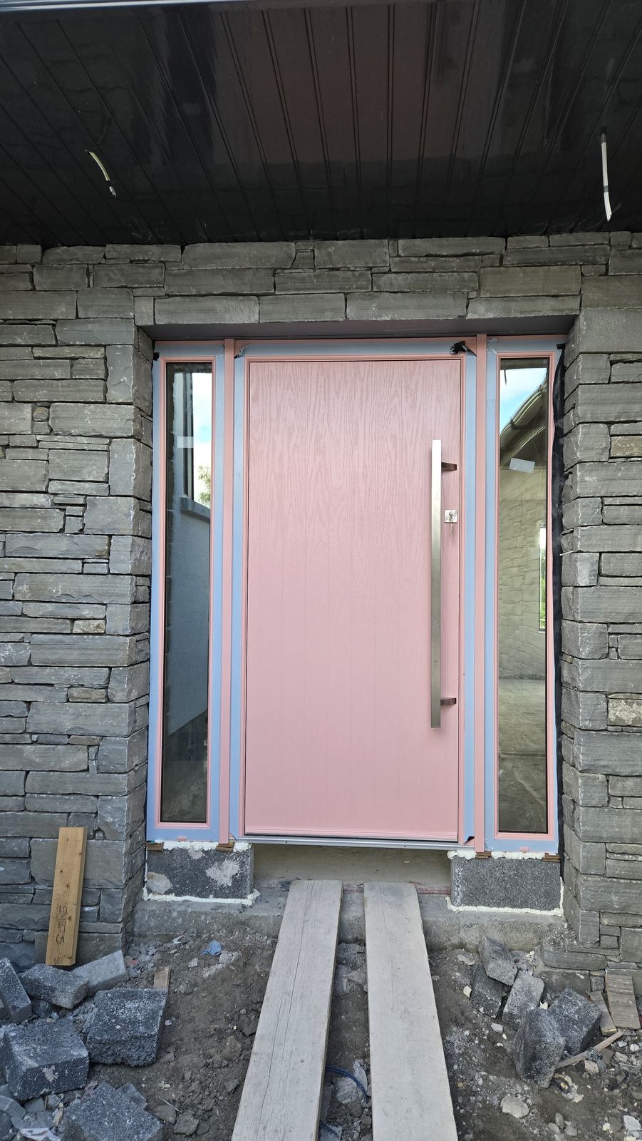 Pink front door with side panels on a new build